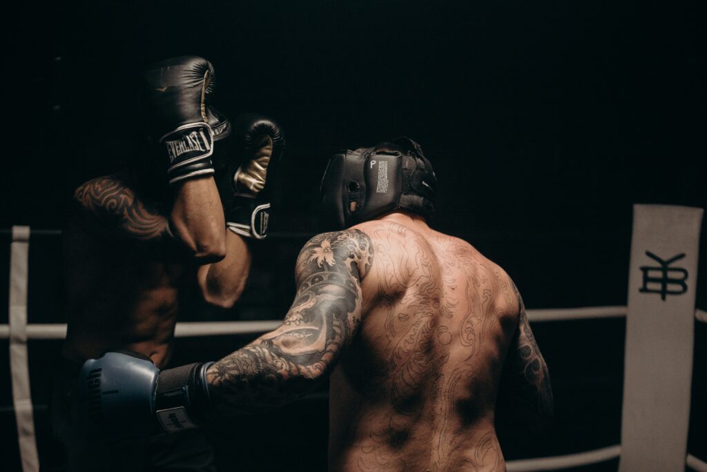 2 Boxers in the ring. 1 Boxer using a left hook. The other boxer guarding his face