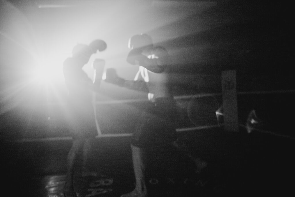 2 boxers doing sparring, while wearing boxing shoes and boxing gloves