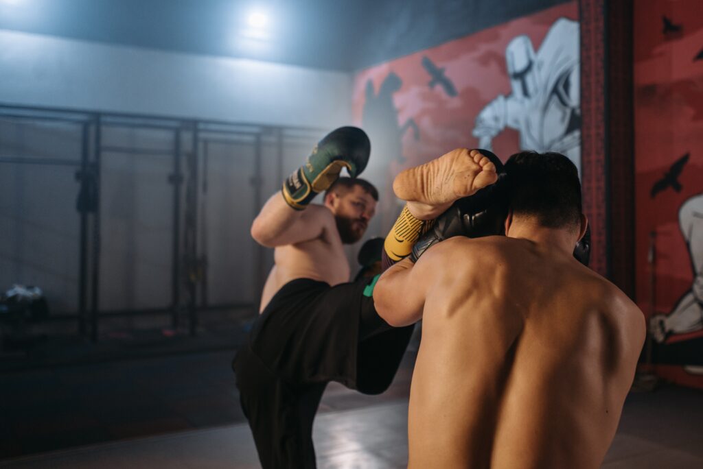 1 fighter kicking a boxer in the head