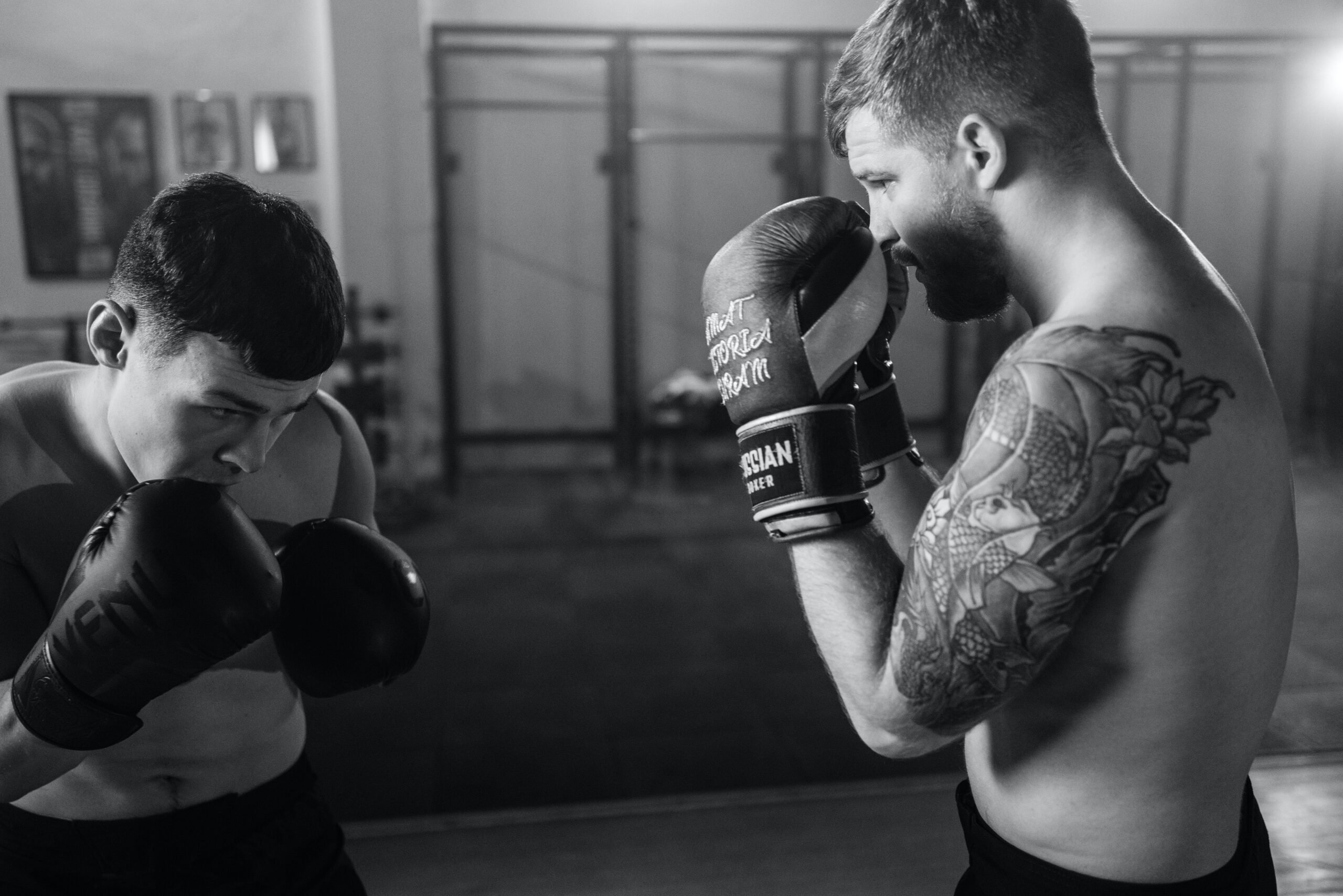 2 boxers practicing sparring. 1 boxer guarding his face and the other is about to throw a body punch.