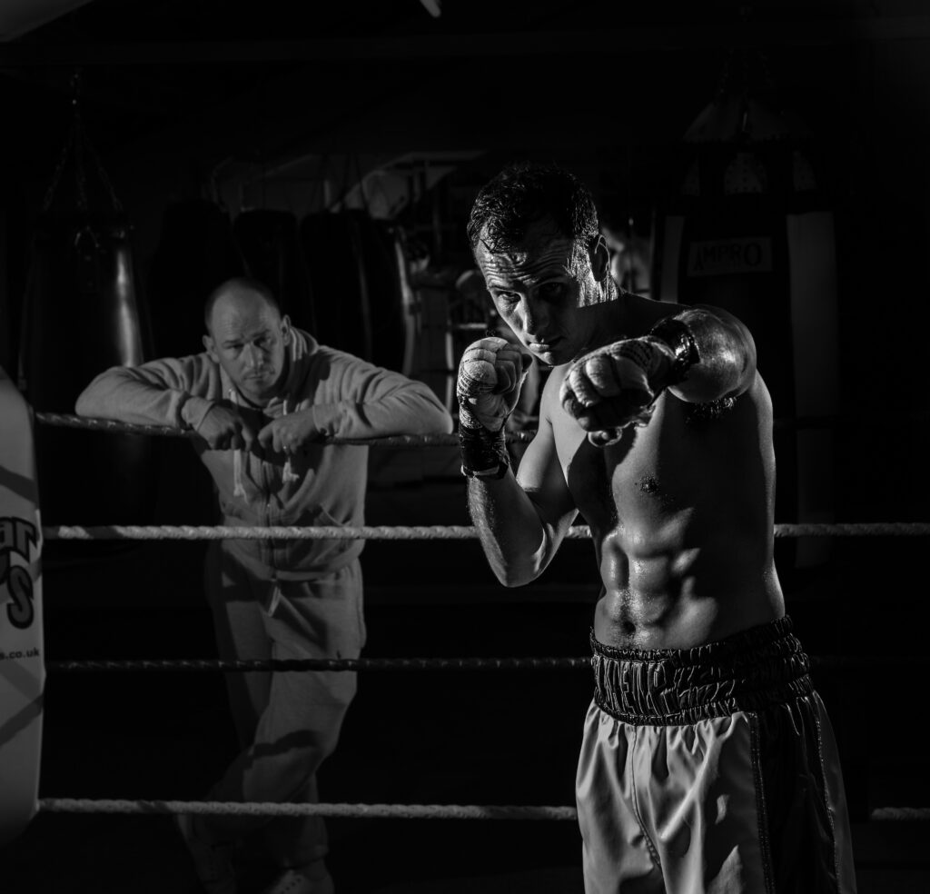 A boxer and his coach, standing in a boxing ring.