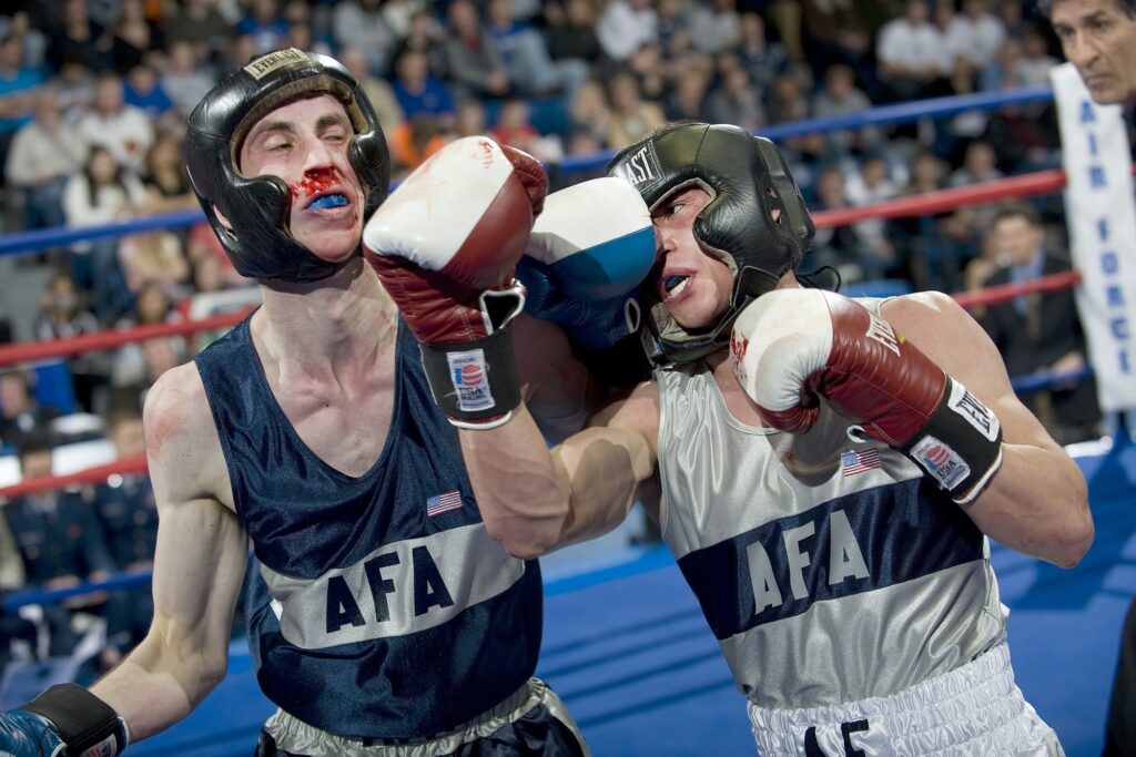 2 boxers fighting in a boxing ring. 1 fighter punching, resulting in knockout.