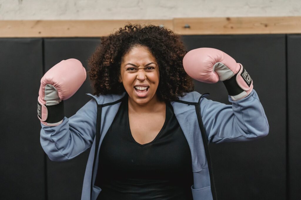 excited young black sportswoman showing biceps after boxing training, boxing at home