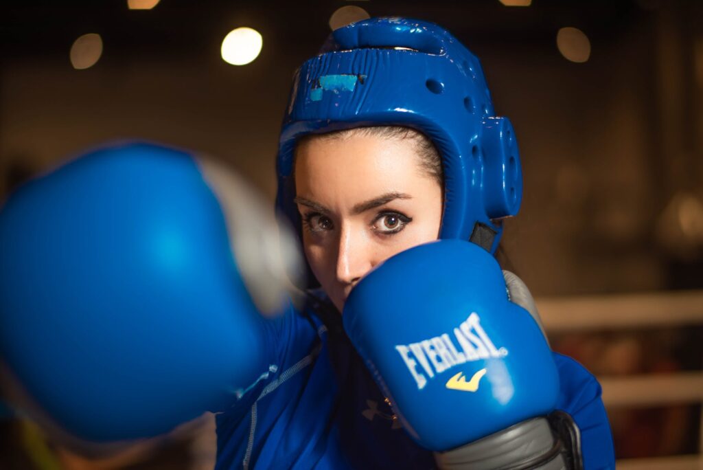 female boxer with blue headgear and boxing gloves, boxing equipment